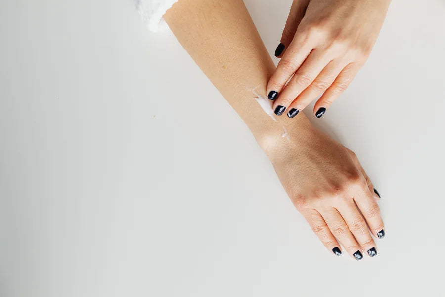 Hands applying cream to skin
